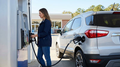 A driver refueling their modern car rental at a sunny gas station in the United States