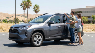 A car rental with a roof box driving on a scenic coastal highway in California