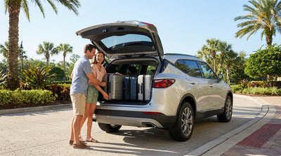 Open trunk of a white SUV car hire with three large suitcases waiting to be loaded in Orlando