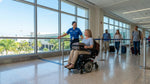 A traveler in a wheelchair at the Miami International Airport car hire center waiting for mobility assistance