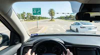 A modern car hire vehicle navigating a multi-lane intersection under a clear blue sky in Texas