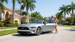 A red convertible car hire driving down a scenic coastal highway in Florida with palm trees and ocean views