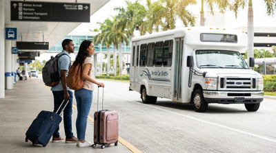 Travelers waiting for a car rental shuttle under the purple sign outside Tom Bradley International Terminal at LAX