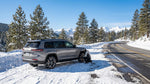 A car hire driving on a winding snow-covered road through the mountains of Lake Tahoe, California