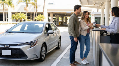 A white convertible car hire driving on a sunny road lined with tall palm trees in Los Angeles