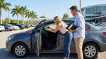 A modern car hire sedan parked under a palm tree on a sunny day in Florida