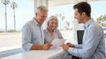 Senior couple standing next to a white car hire parked on a sunny California coastal road