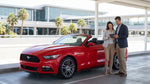 A red sports car rental driving down the Las Vegas Strip at night past the bright neon signs and casino lights