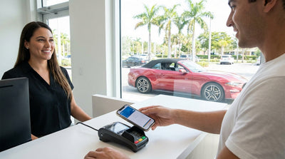 A person uses a smartphone to complete a car hire payment at a rental desk in a sunny Miami airport