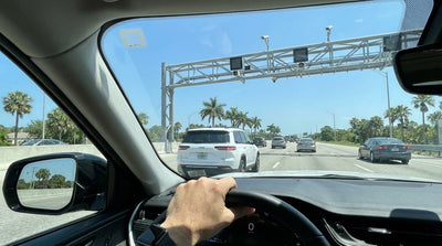 A white car hire driving towards a cashless toll on a palm-tree-lined highway in Florida