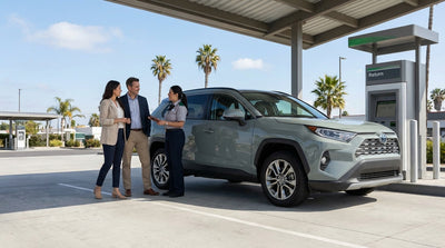 A red convertible car hire driving along a sunny, winding coastal road in California overlooking the blue ocean