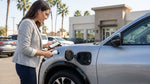 A modern electric car rental charging at a station with palm trees under a sunny California sky