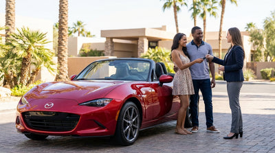 A convertible car rental cruises down the Las Vegas Strip at night, illuminated by bright neon casino lights