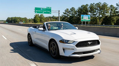 A modern car rental driving on a sunny highway with palm trees on the open road in Florida