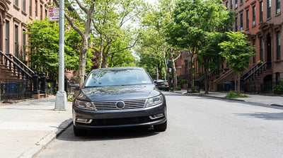 A line of cars, including a car hire, parked along a residential New York street by a parking rules sign