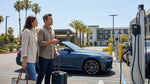 A sleek electric car rental driving along a sunlit coastal highway with ocean views in California