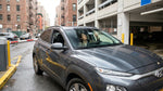 A car rental drives across the Brooklyn Bridge with the scenic New York City skyline in the background