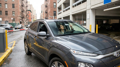 A car rental drives across the Brooklyn Bridge with the scenic New York City skyline in the background