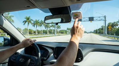A modern car rental drives under a SunPass toll gantry on a sunny highway in Florida
