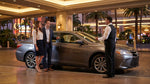 A luxury car hire pulls up to a casino valet stand under the bright neon lights of Las Vegas