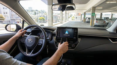 A person plugging their phone into a car rental dashboard with a view of the streets of San Francisco