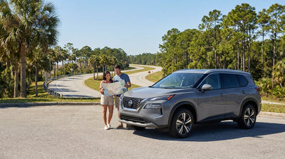 A white car rental on a sunny coastal highway in Florida with palm trees and blue ocean views