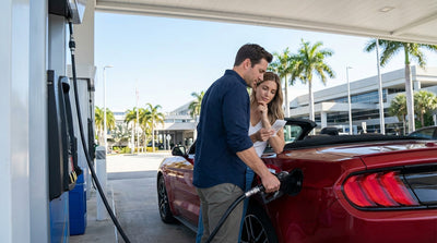 A white convertible car rental driving past colorful Art Deco buildings on a sunny day in Miami
