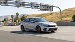 White car rental driving under an electronic toll gantry on a California highway
