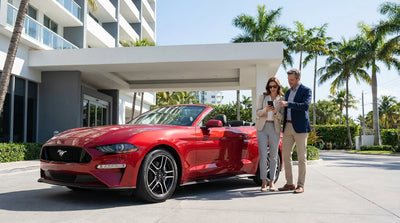 A red convertible car hire on a sunny, palm-tree-lined street in Miami