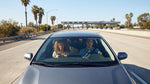 A modern car rental driving on a sunny highway with palm trees in California
