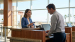 Customer handing a credit card to an agent at a bright car rental counter in Texas