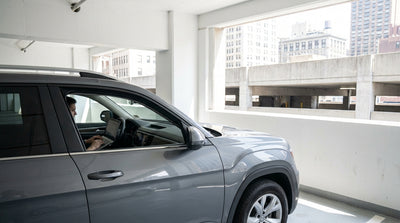 A white car rental stopped at the entrance barrier of a modern New York parking garage
