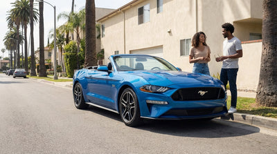 A convertible car hire parked with its roof down on a sunny, palm-lined street in Los Angeles
