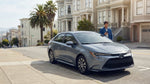 A modern car rental parked on a steep hill with Victorian houses in the background in San Francisco