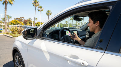 Dashboard of a California car hire showing Apple CarPlay with a sunny, palm-lined road seen through the windshield