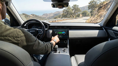An electric car rental driving down a steep, winding mountain road in California with a scenic view