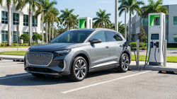 White electric car rental plugged into a charging station under palm trees in Florida
