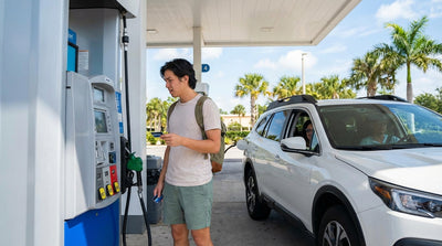 A driver refueling a white car hire at a sunny gas station with palm trees in Florida
