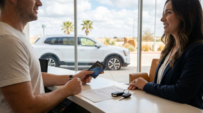 A convertible car hire drives down a long, open road in the Texas desert under a vibrant sunset sky