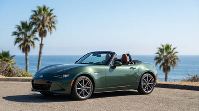 A convertible car hire drives along the winding coastal highway in Big Sur, California at sunset