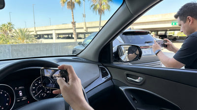 A driver photographs the dashboard fuel gauge and odometer of a car rental in a Los Angeles airport garage