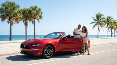A stylish convertible car rental driving on a sunny Ocean Drive in Miami next to palm trees and the beach
