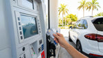 Hand inserting a credit card into a gas pump terminal beside a car rental in Miami