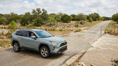 A white car rental stopped before a dangerously flooded low-water crossing in Texas