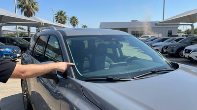 A driver inspects a small chip on the windscreen of their Texas car rental vehicle before driving
