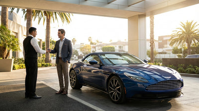 A luxury sports car rental driving on a sunny road lined with palm trees in Los Angeles