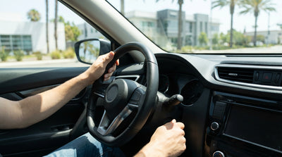 A person's hands on the steering wheel of a car rental with the key in the ignition in California