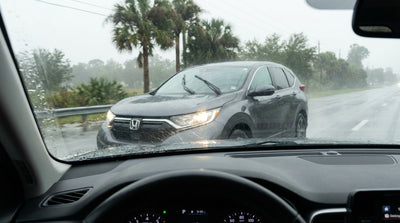 A car hire drives on a wet Florida highway in a downpour with its headlights and windshield wipers on