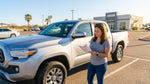 A white car rental parked on a paved road overlooking a desert landscape in Texas