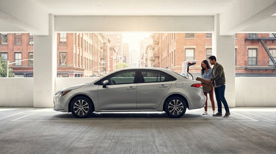 A silver car hire driving across the Brooklyn Bridge towards the iconic New York City skyline
